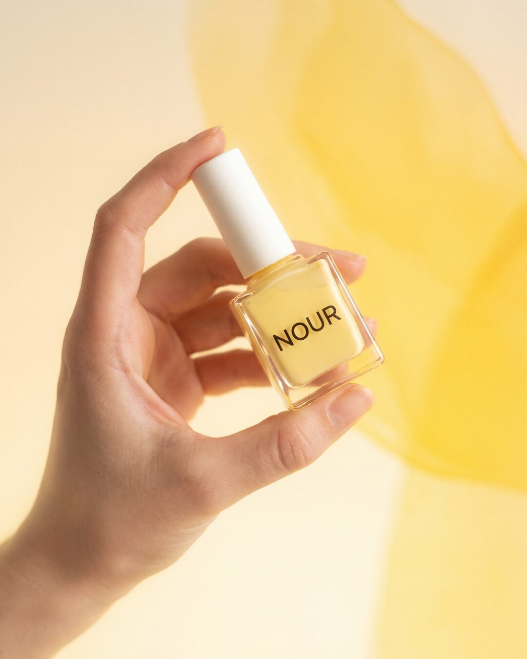 Generated NOUR perfume image held against a yellow flower